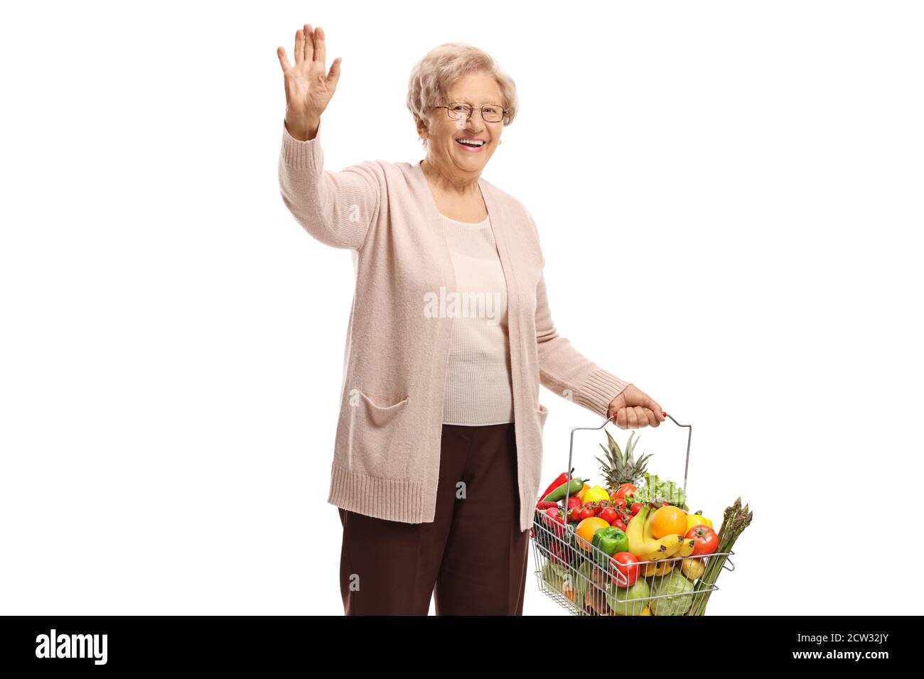 Older woman with fruits and vegetables in a shopping basket waving ...