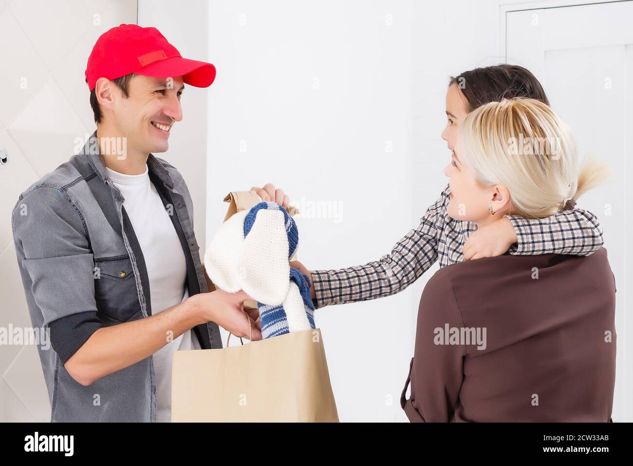 mother and daughter receive order from delivery man, delivery of toys and goods for children at