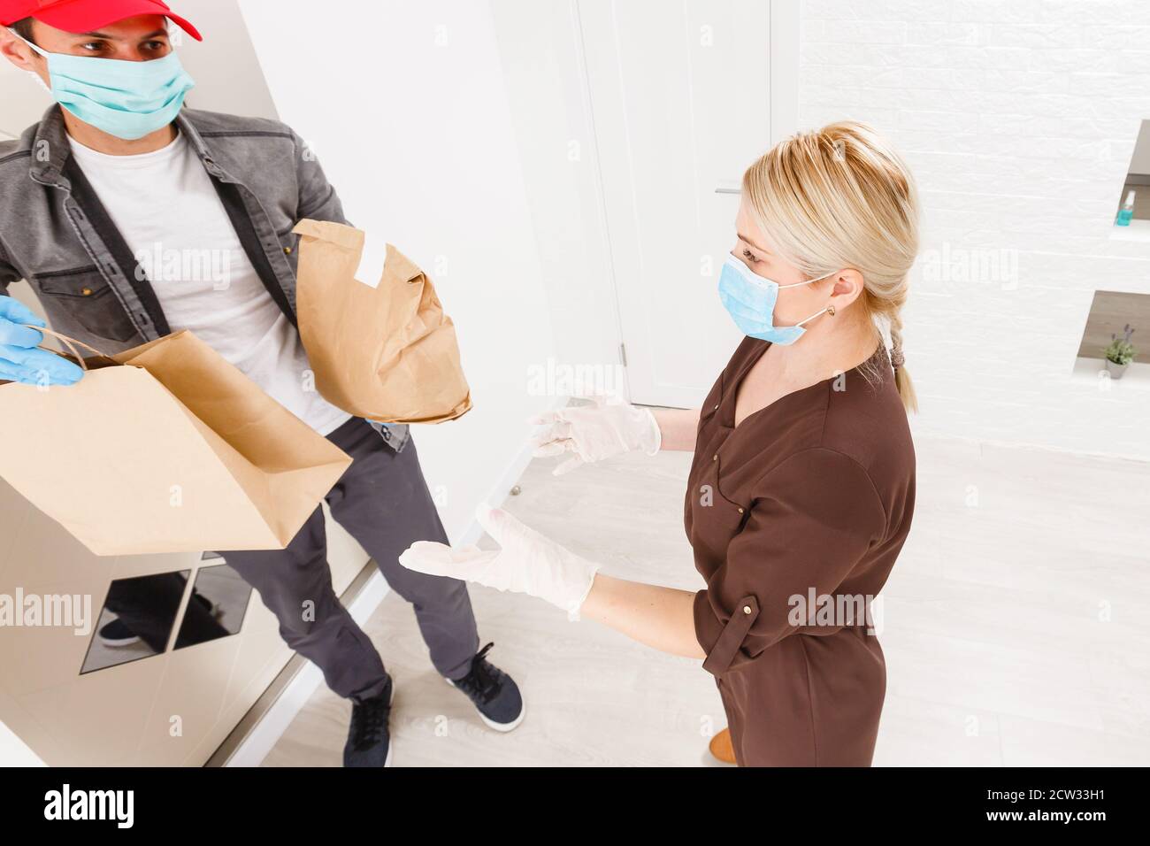 Young woman wearing medical mask receiving orderd food from the ...