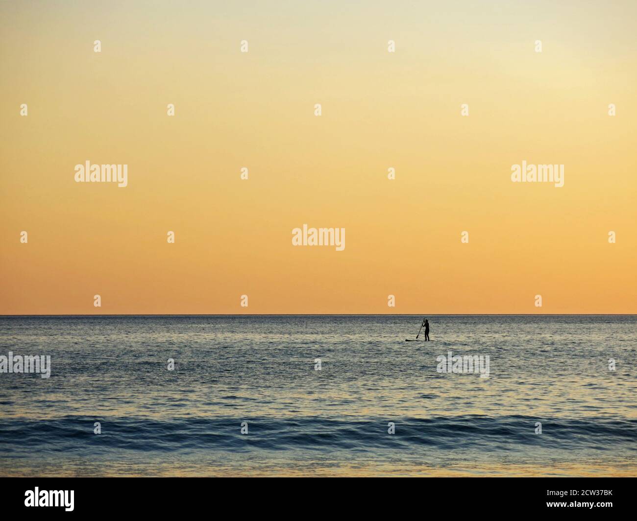 Female person standing up paddleboarding during sunset at Plakias beach, Crete, Greece. Stock Photo