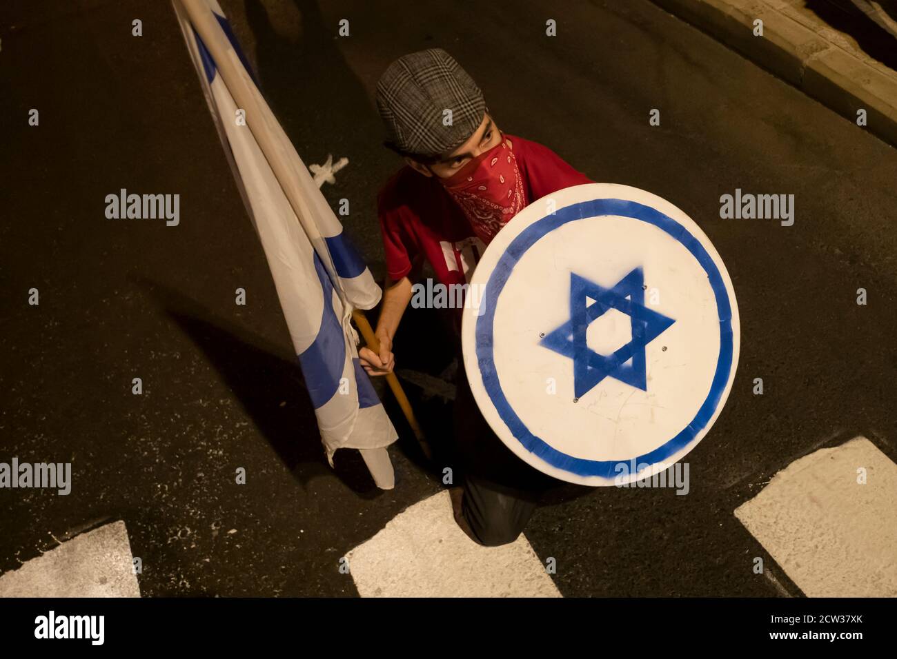 JERUSALEM, ISRAEL - SEPTEMBER 26: A protester holds a shield with the Jewish Star of David during a mass demonstration near prime minister's official residence amid a nationwide lockdown aimed at curbing the coronavirus pandemic on September 26, 2020 in Jerusalem, Israel. A wave of protests has swept Israel in recent months to demand Netanyahu's resignation over his indictment on corruption charges and handling of the coronavirus pandemic, with the largest weekly demonstration taking place every weekend in Jerusalem. Stock Photo