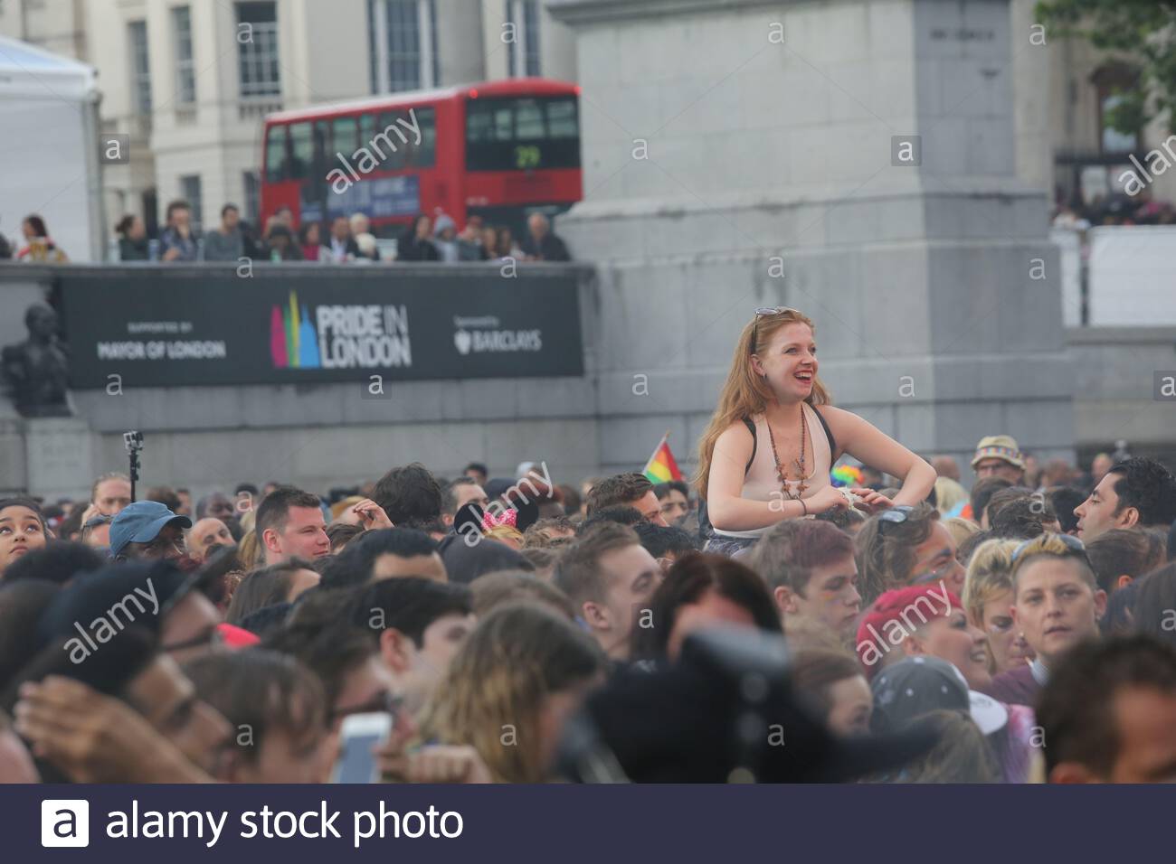 A young woman high above the crowd in Trafalgar Square as the Pride London festival concert continues a day after the Brexit result. Stock Photo