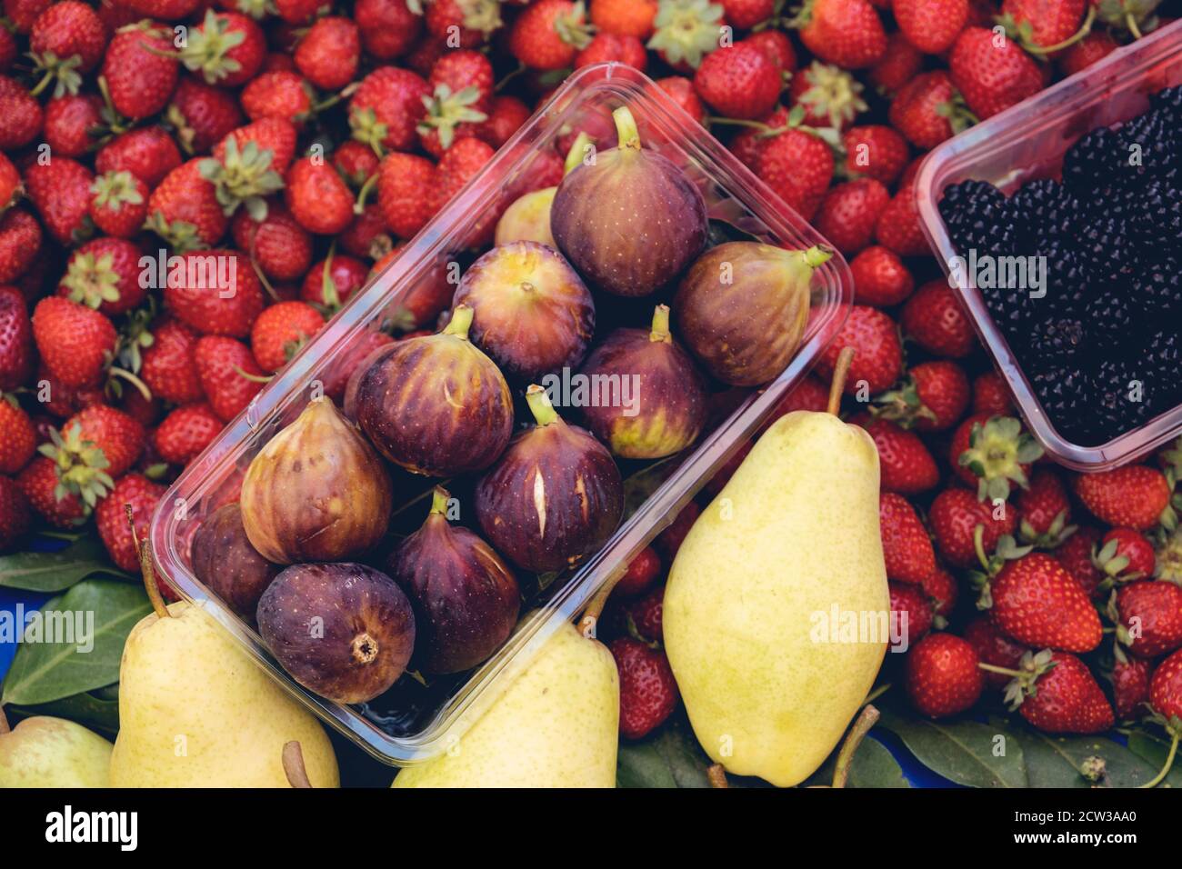 Purple figs, strawberries, blackberries and pears are standing at a