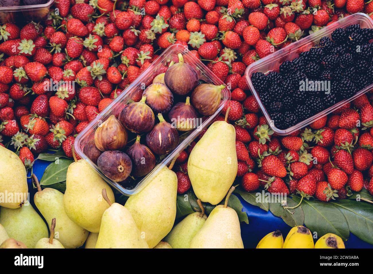 Purple figs, strawberries, blackberries and pears are standing at a