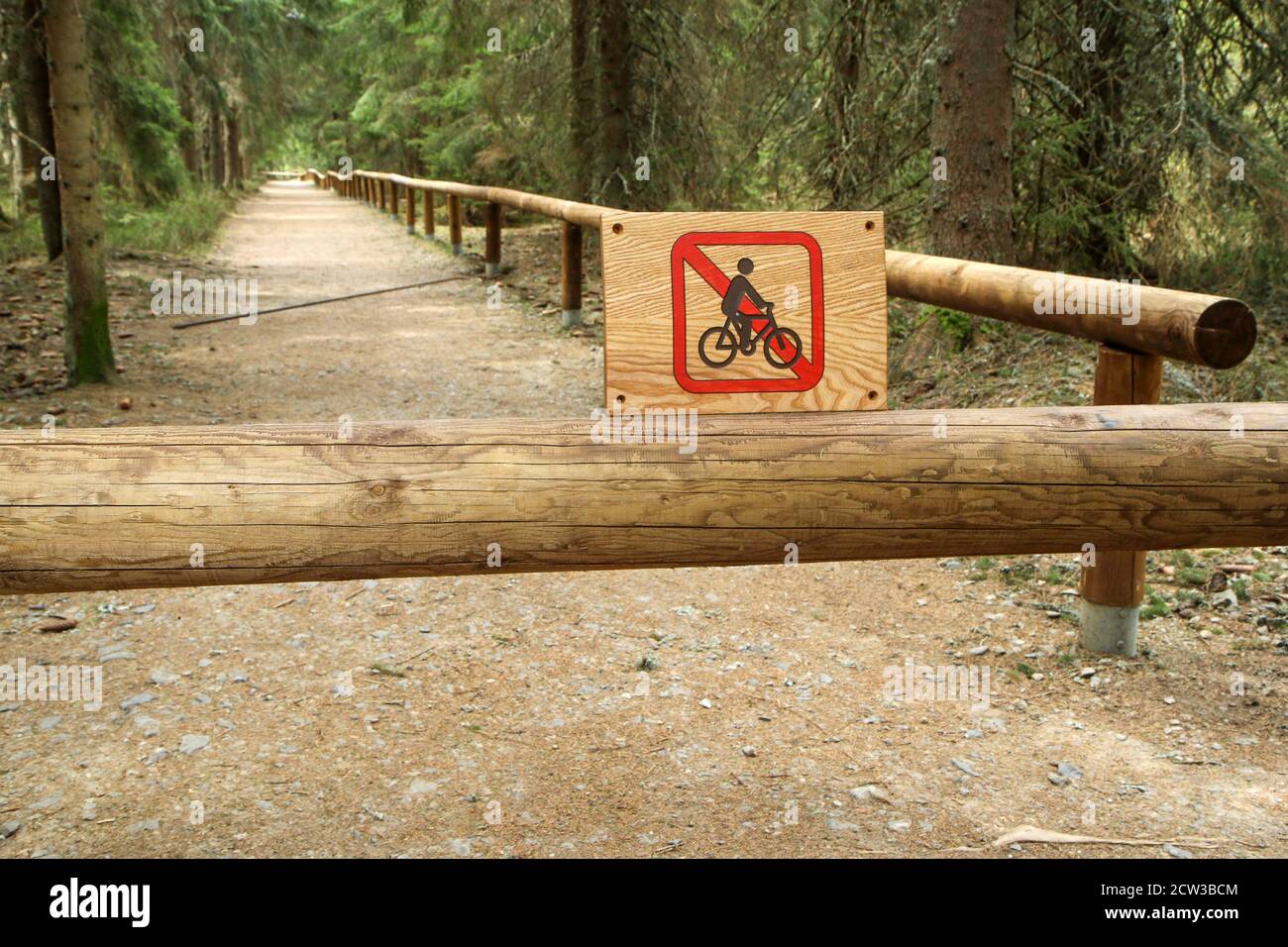 The footpath deep in the woods in the protected area with a sign showing the restriction of entry for the cyclists. Stock Photo