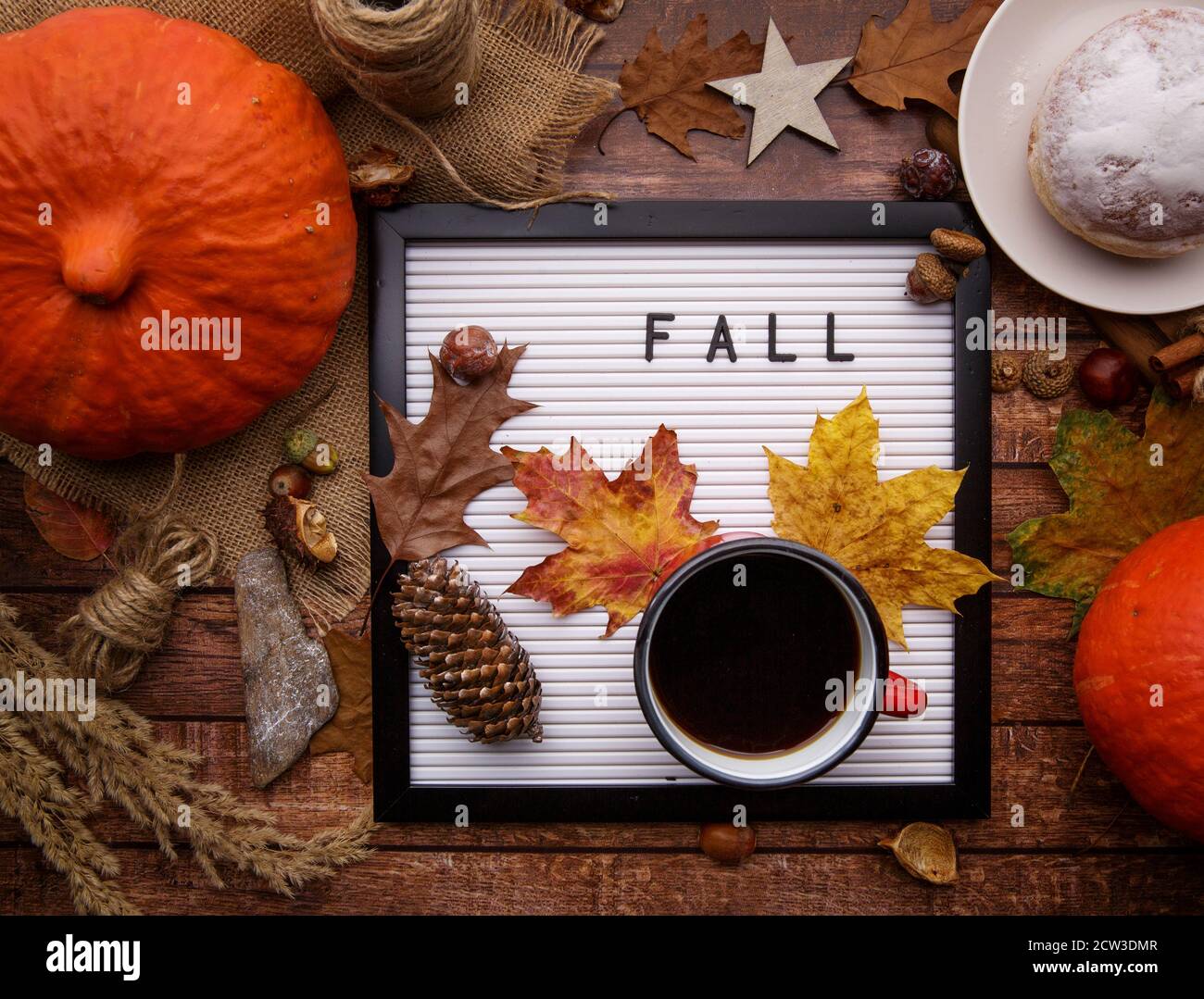 On the table with pumpkins is board with the inscription and a cup of coffee. Stock Photo