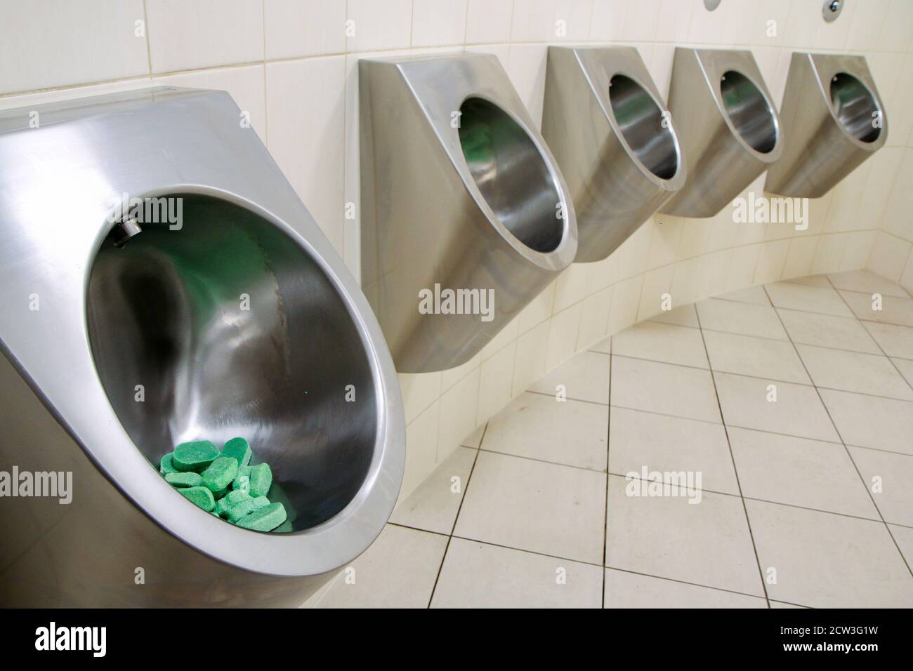 The detail of a row of modern metal urinals, which are full with the small soaps for a precise hygiene. Stock Photo