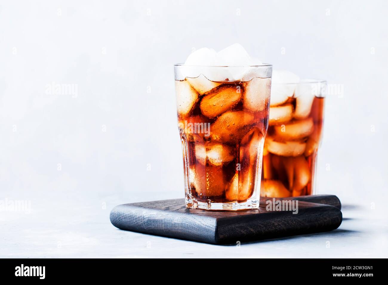 Alcoholic cocktail of rum-cola with ice, gray background, selective focus Stock Photo
