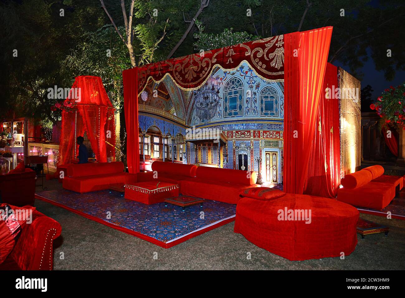 Beautifully decorated red sofas or couch ready for the guests sitting at a wedding ceremony in backyard, night ceremony venue, wedding event decor con Stock Photo