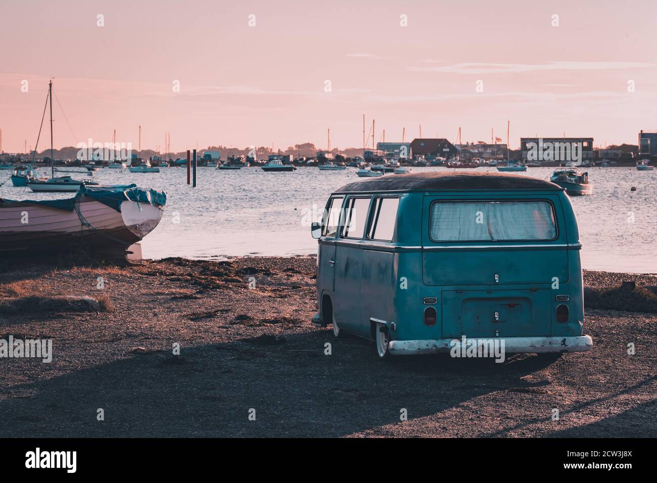 A vintage camper van parked near the sea at sunset Stock Photo