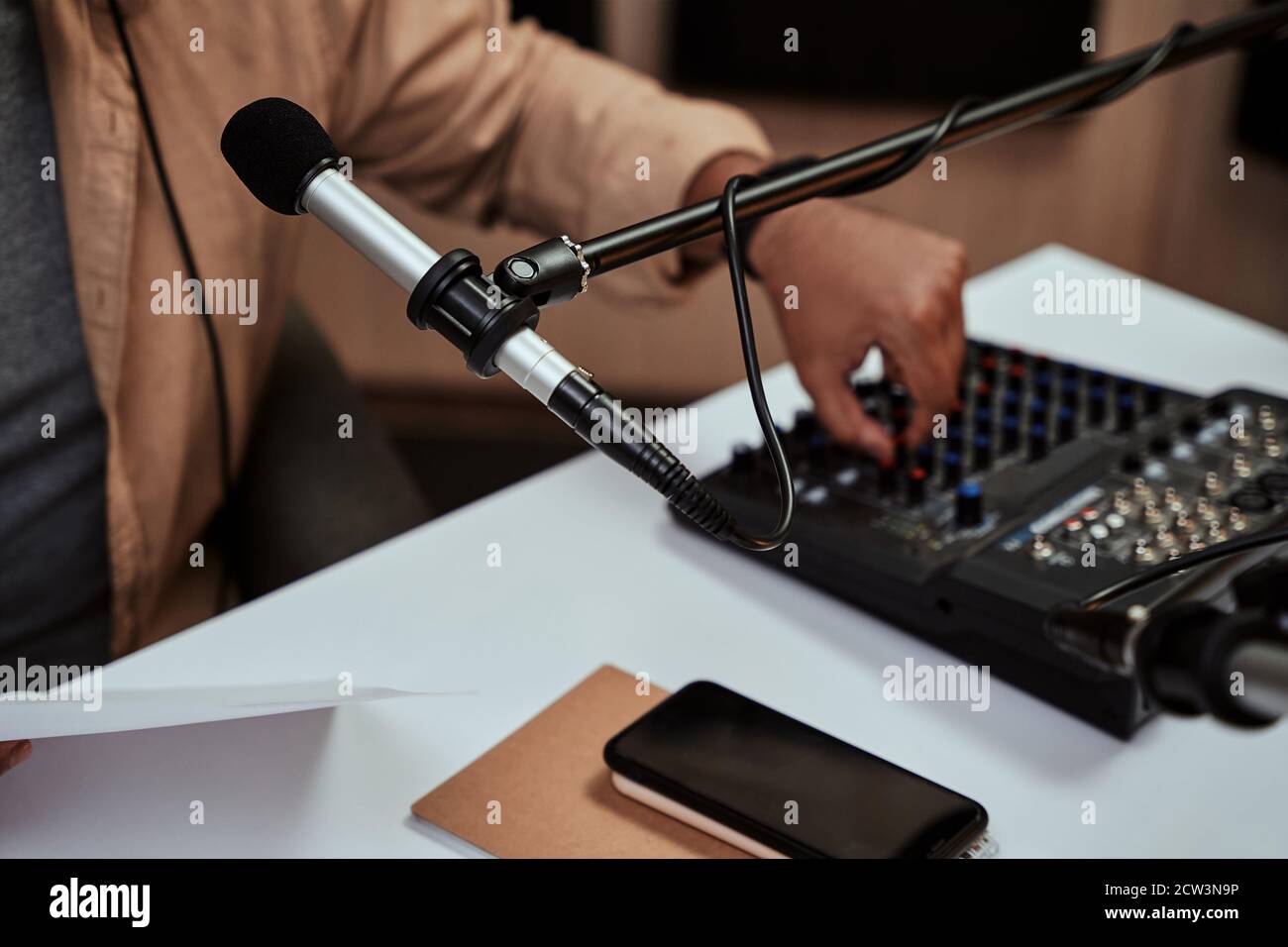 Close up of microphone at radion station studio. Male host working on a sound mixing desk in