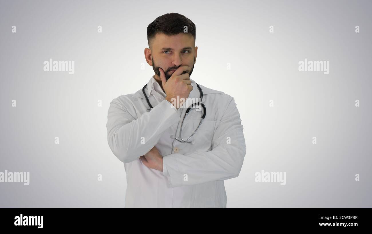 Doctor standing and thinking hard on gradient background. Stock Photo
