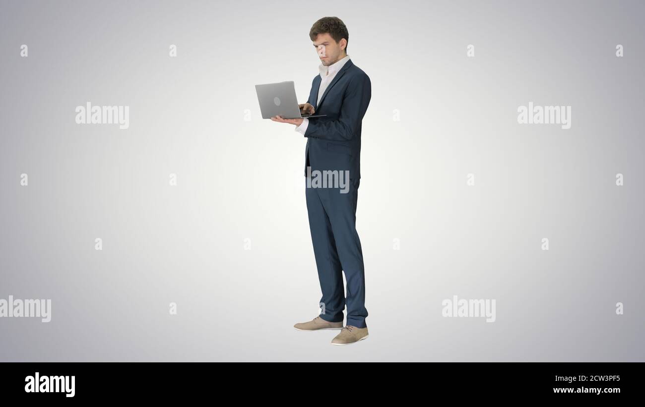 Concentrated young businessman working on laptop while standing Stock Photo