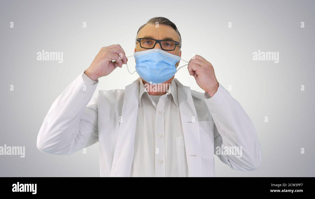 Male Doctor taking off protective Medical mask and smiling to ca Stock Photo
