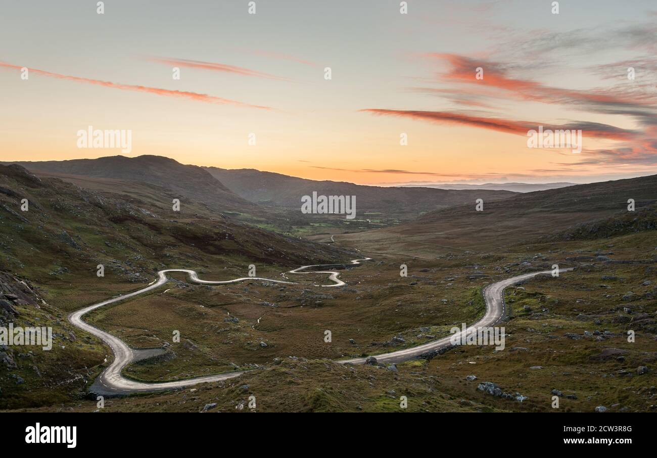Healy Pass, Cork, Ireland. 27th September, 2020. Autumnal dawn light reflects on the R574, a serpentine like mountain road that meanders through the Caha Mountains from Castletownbere to the Healy Pass in West Cork, Ireland.  - Credit; David Creedon / Alamy Live News Stock Photo