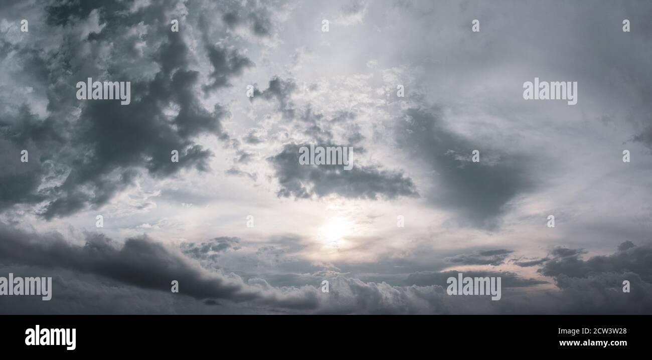 Panorama of grey high layered grey epic clouds with sun and sunlight on sky. Heaven cloudscape air view Stock Photo