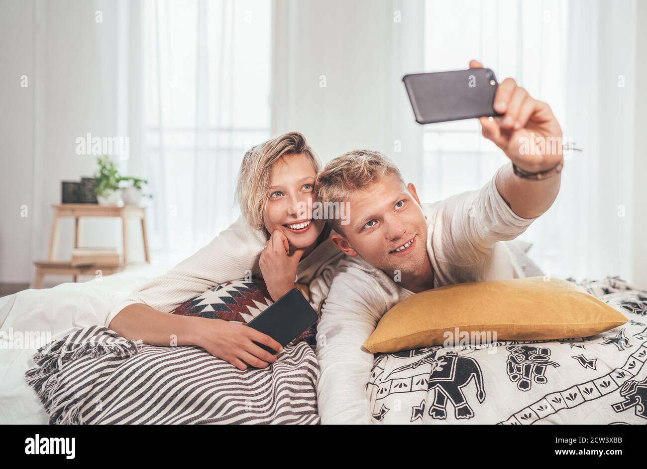 Cheerful young adults сouple in pajamas taking a selfie photo using a ...