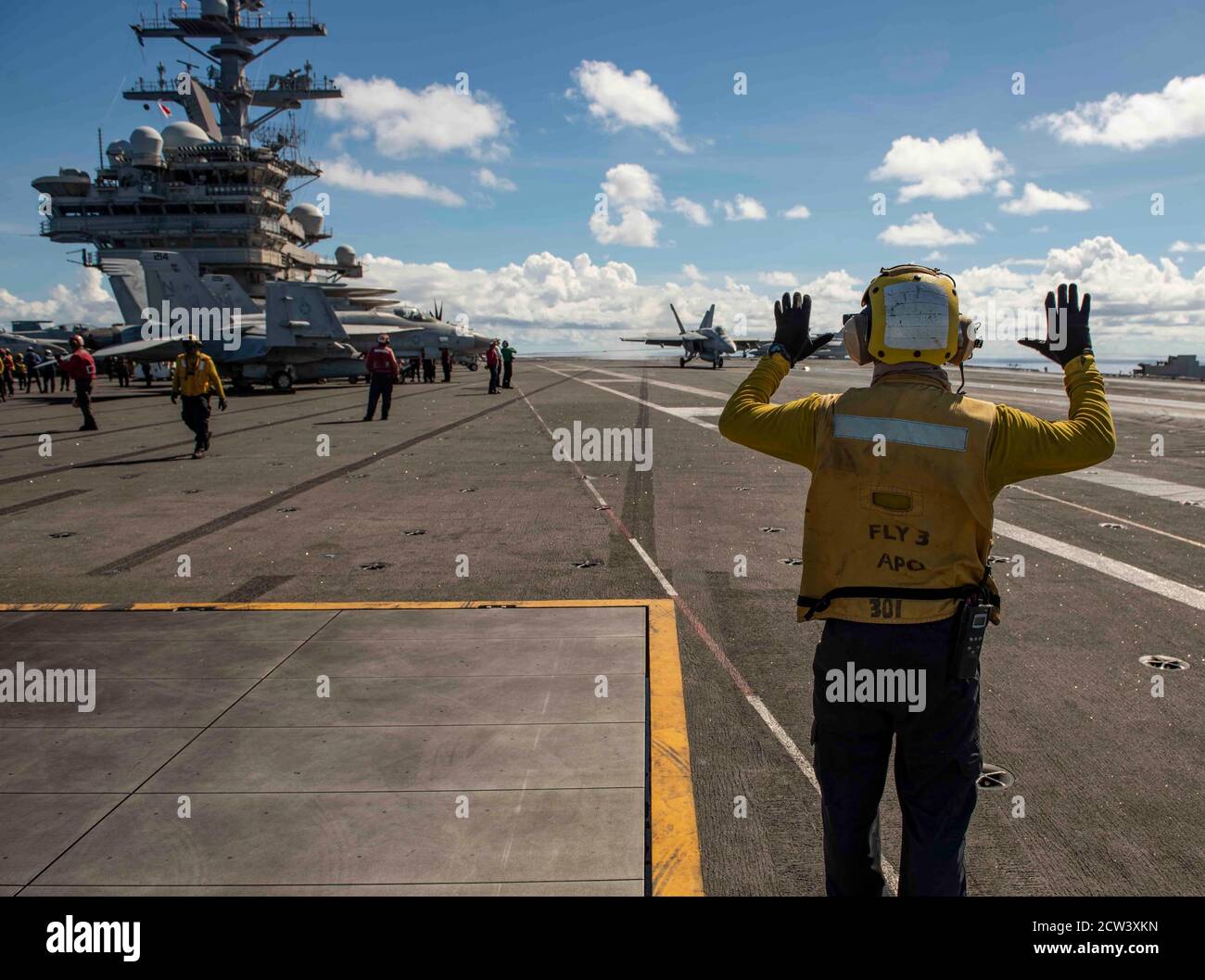 Aviation Boatswain’s Mate (Handling) 3rd Class Zachary Fite, from Philadelphia, signals an F/A-18E Super Hornet, attached to the Dambusters of Strike Fighter Squadron (VFA) 195, as it lands on the flight deck of the Navy’s only forward-deployed aircraft carrier USS Ronald Reagan (CVN 76). Ronald Reagan, the flagship of Carrier Strike Group 5, provides a combat-ready force that protects and defends the United States, as well as the collective maritime interests of its allies and partners in the Indo-Pacific region. (U.S. Navy photo by Mass Communication Specialist 2nd Class Erica Bechard) Stock Photo