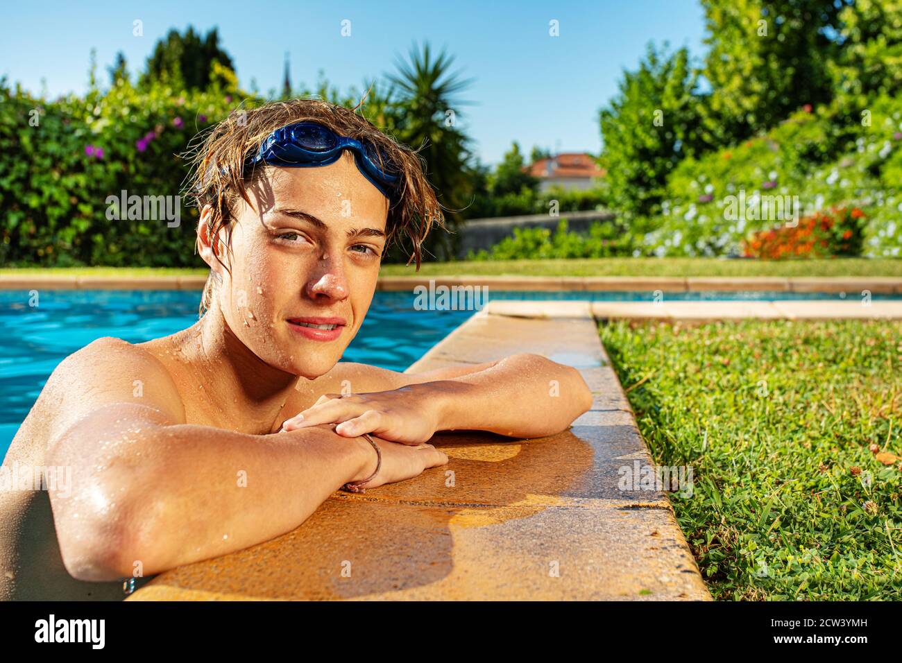 View from side of a handsome boy on the border of swimming pool with calm expression Stock Photo