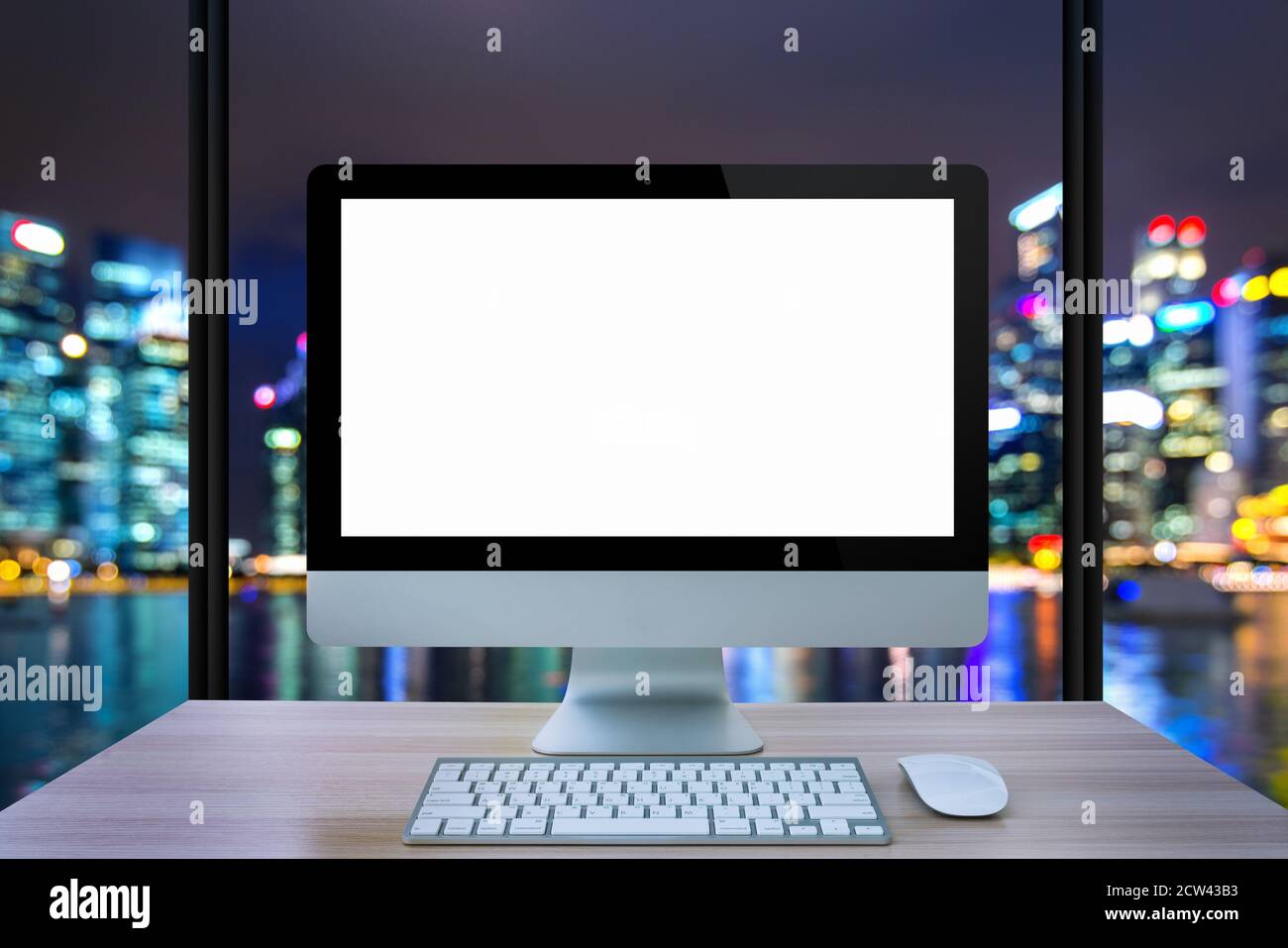 Computer monitor, mouse, keyboard on table with cityscape background
