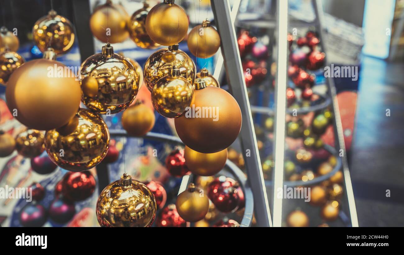 Close up of christmas toys suspended on metal construction in hall in shopping center. Yellow christmas balls hanging on strings for room decoration Stock Photo