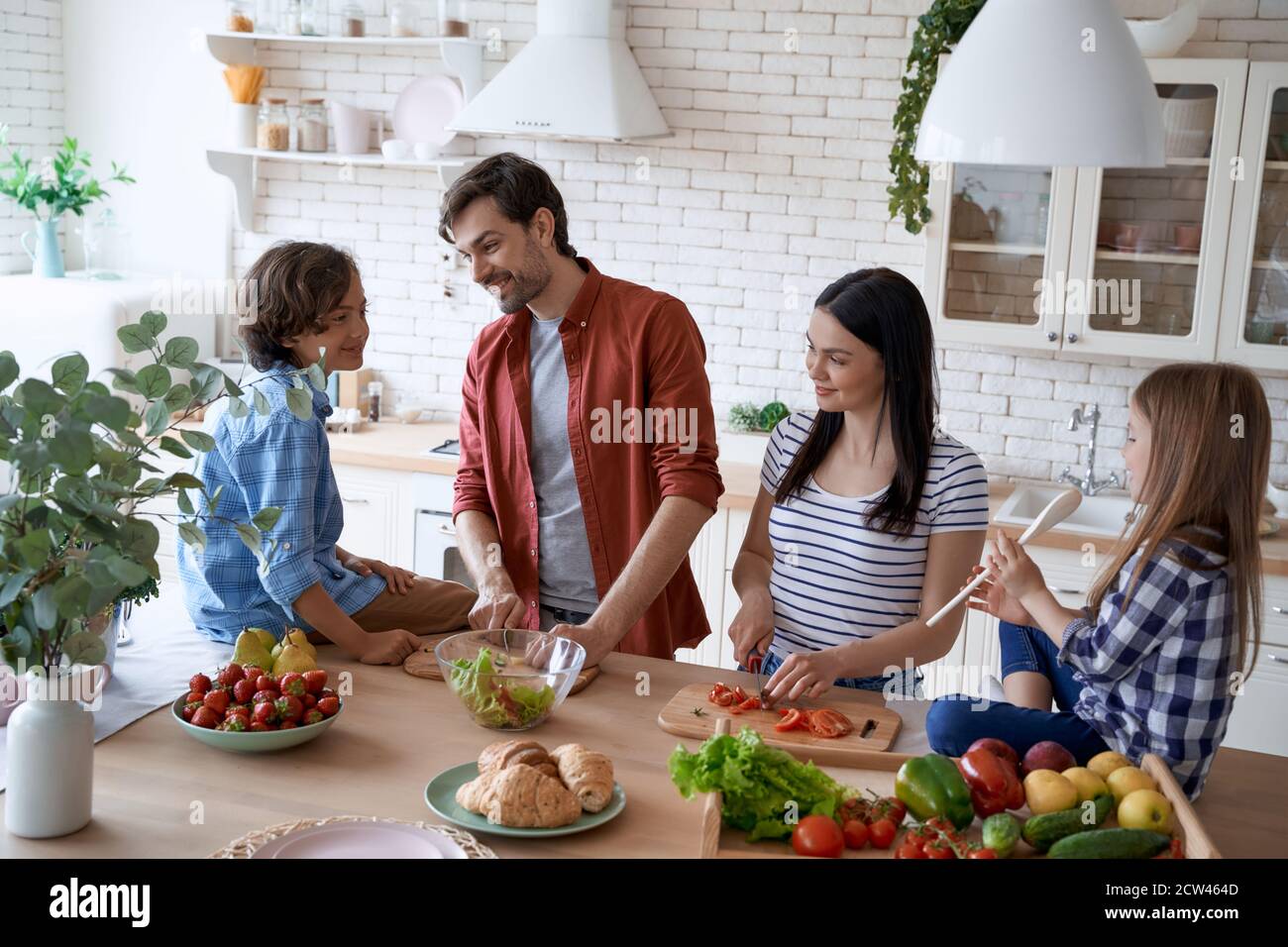 Preparing a salad. Lovely family of four cooking together in the modern  kitchen at home Stock Photo - Alamy