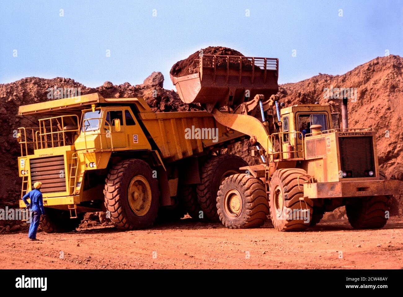 Bauxite mine Fria Guinea West Africa heavy machinery loading ore into large caterpillar dumper