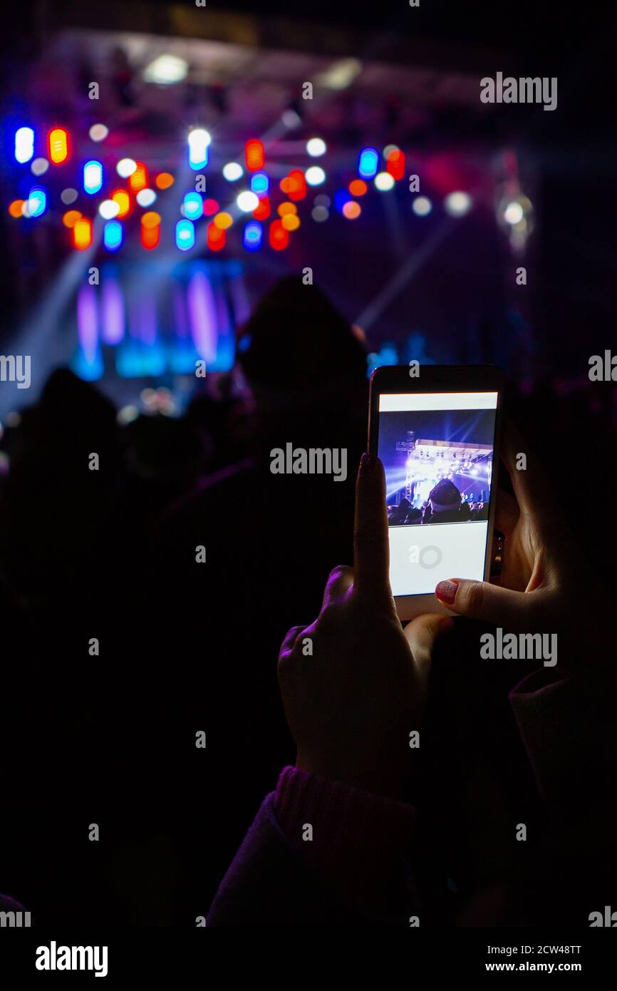 A girl is taking pictures of a street concert on the phone Stock Photo