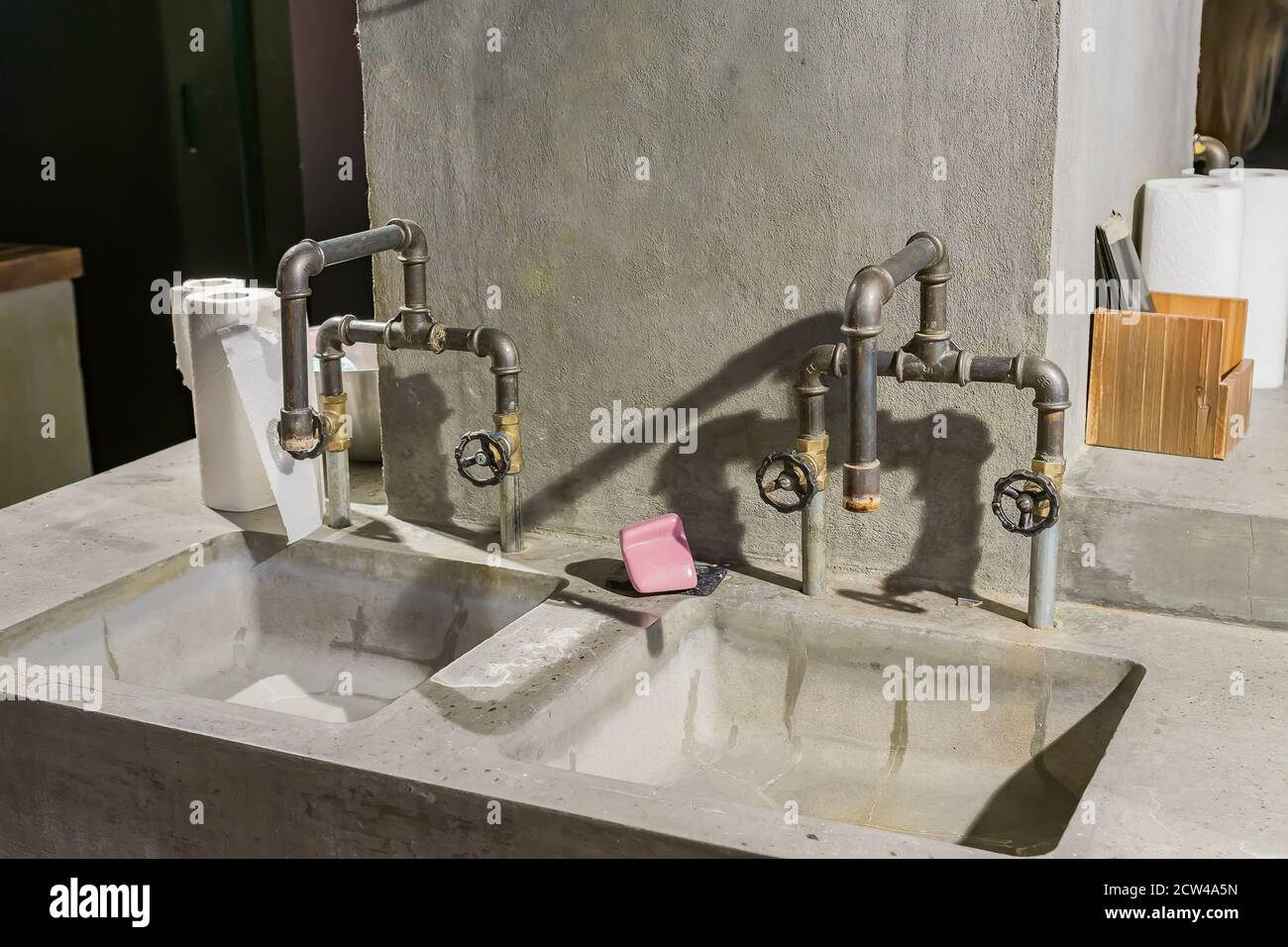 industrial style bathroom. concrete sinks and metal pipe faucet