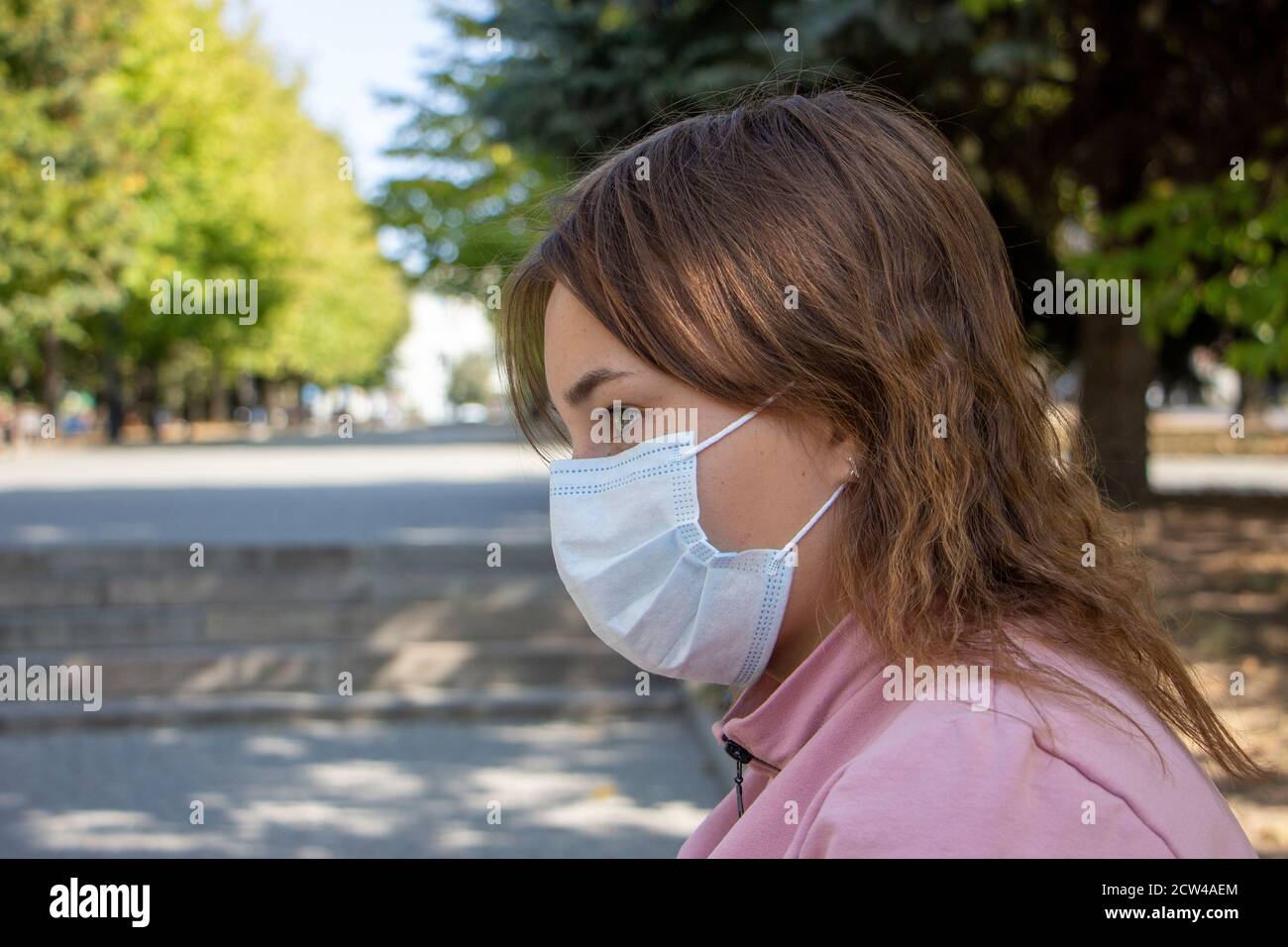 Girl in the fresh air in a mask on the face that protects against viral
