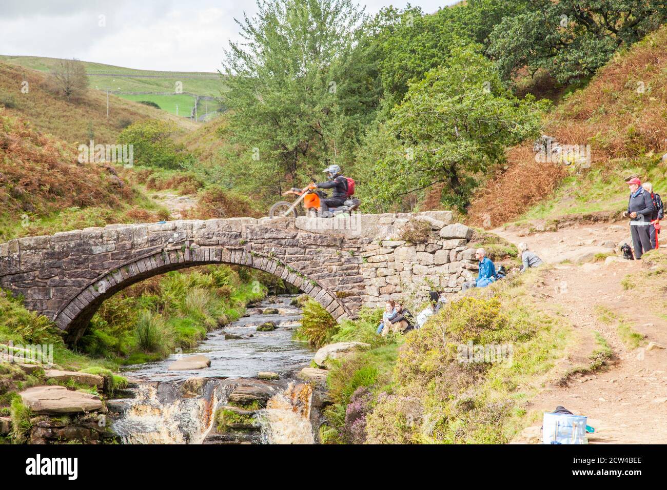 Off road motorcyclists using a green lane trail  crossing the stone bridge at the three shires head  in the Peak District national park  England UK Stock Photo