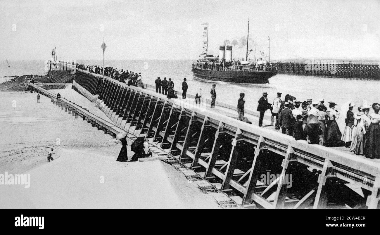 A historical view of the steam turbine ship 'The Queen' run by the South Eastern and Chatham Railway leaving the Calais jetty for either Dover or Folkstone whilst crowds look on. Taken in Calais, Pas-de-Calais, France, from a postcard c.1903-1916. Stock Photo