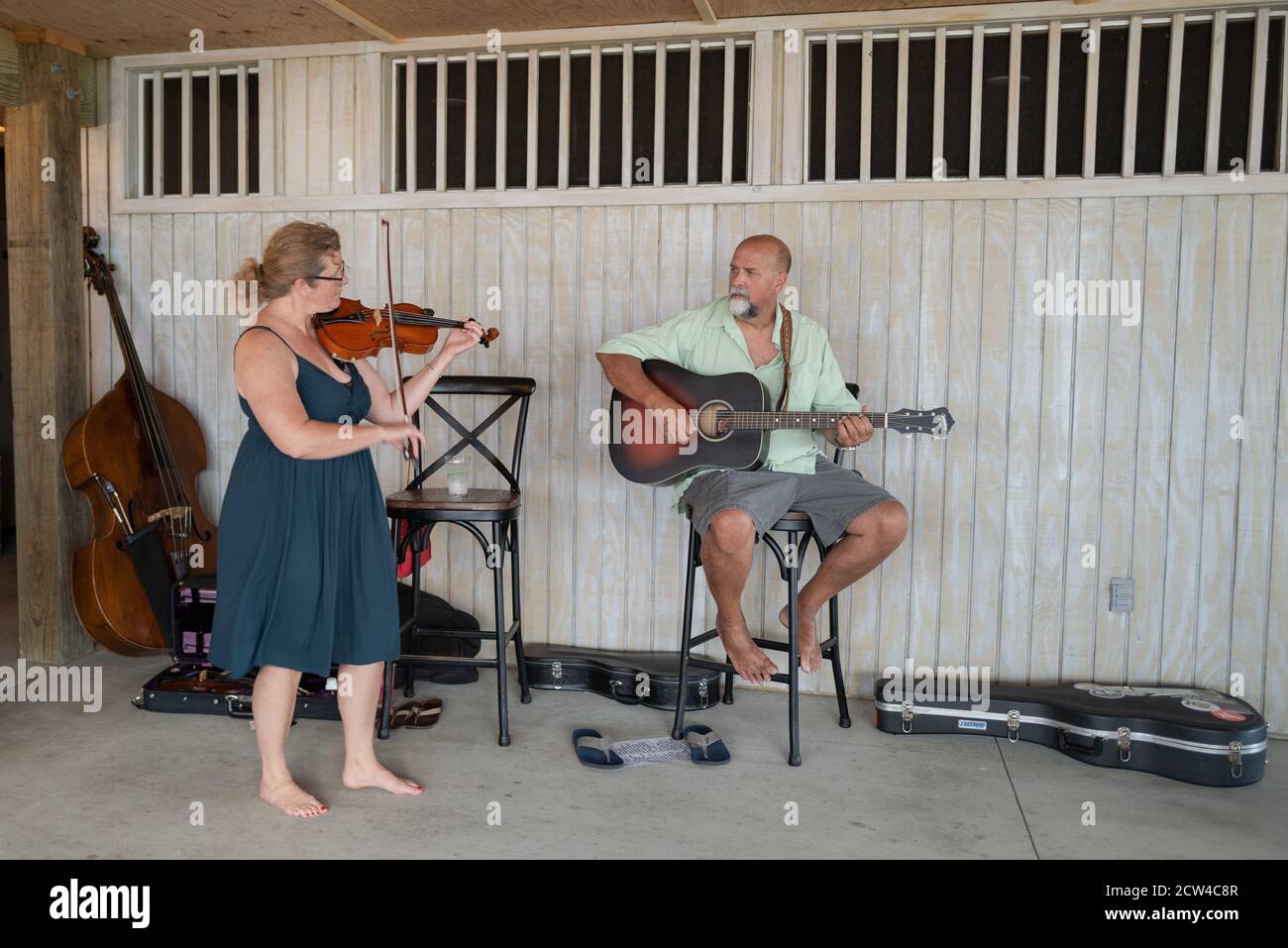 Duck, NC, USA -- June 11, 2020. Photo of  a pair of musicians performing; a woman plays the fiddle and a man plays acoustic guitar. Stock Photo