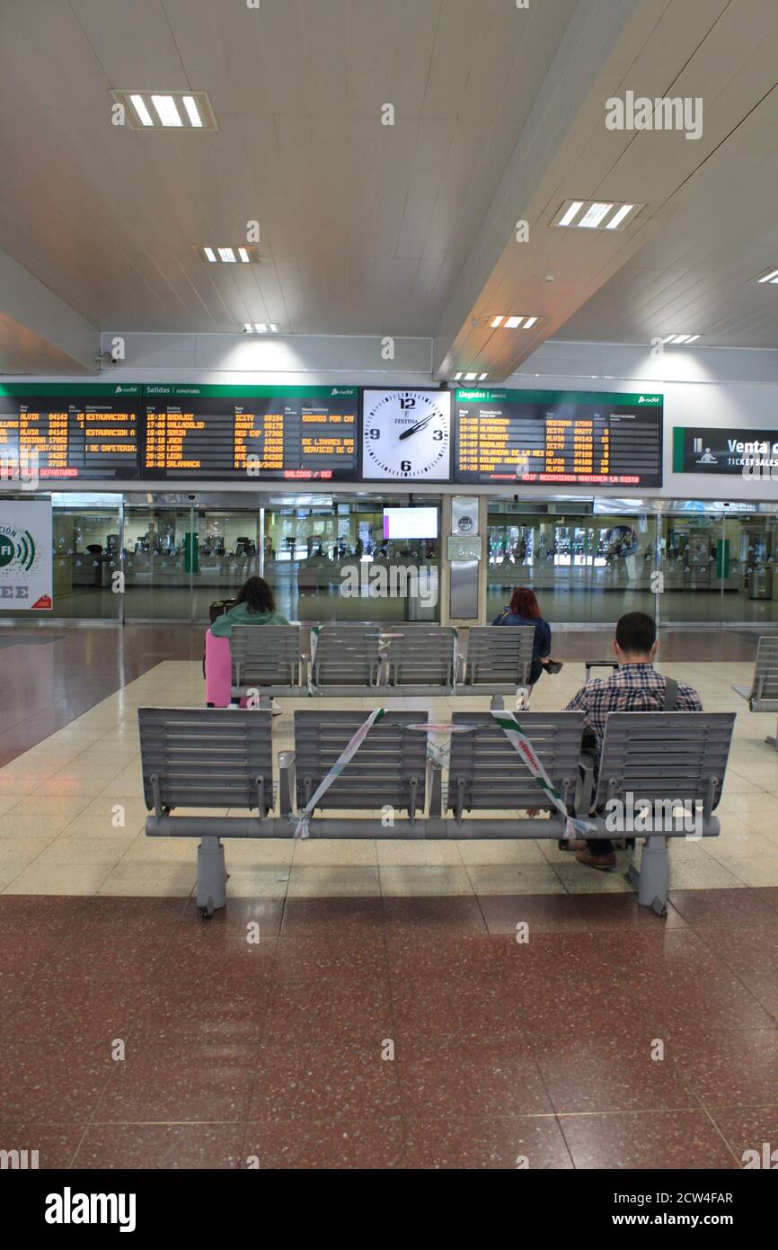 A group of passengers wait next to the screens with information about the train departure at Chamartin station, in Madrid (Spain) in September 2020. Stock Photo