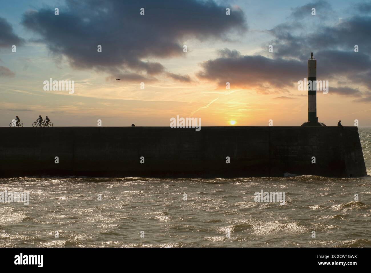 The harbour wall and lighthouse at sundown in Aberystwyth mid Wales, UK Stock Photo