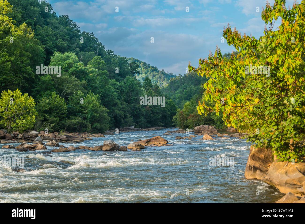 The Ocoee river in Tennessee with its whitewater flowing downstream closeup with the mist in the mountains in the background on a bright sunny day in Stock Photo