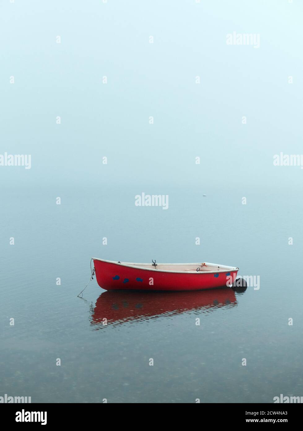 Red rowboat on misty overcast morning. Stock Photo