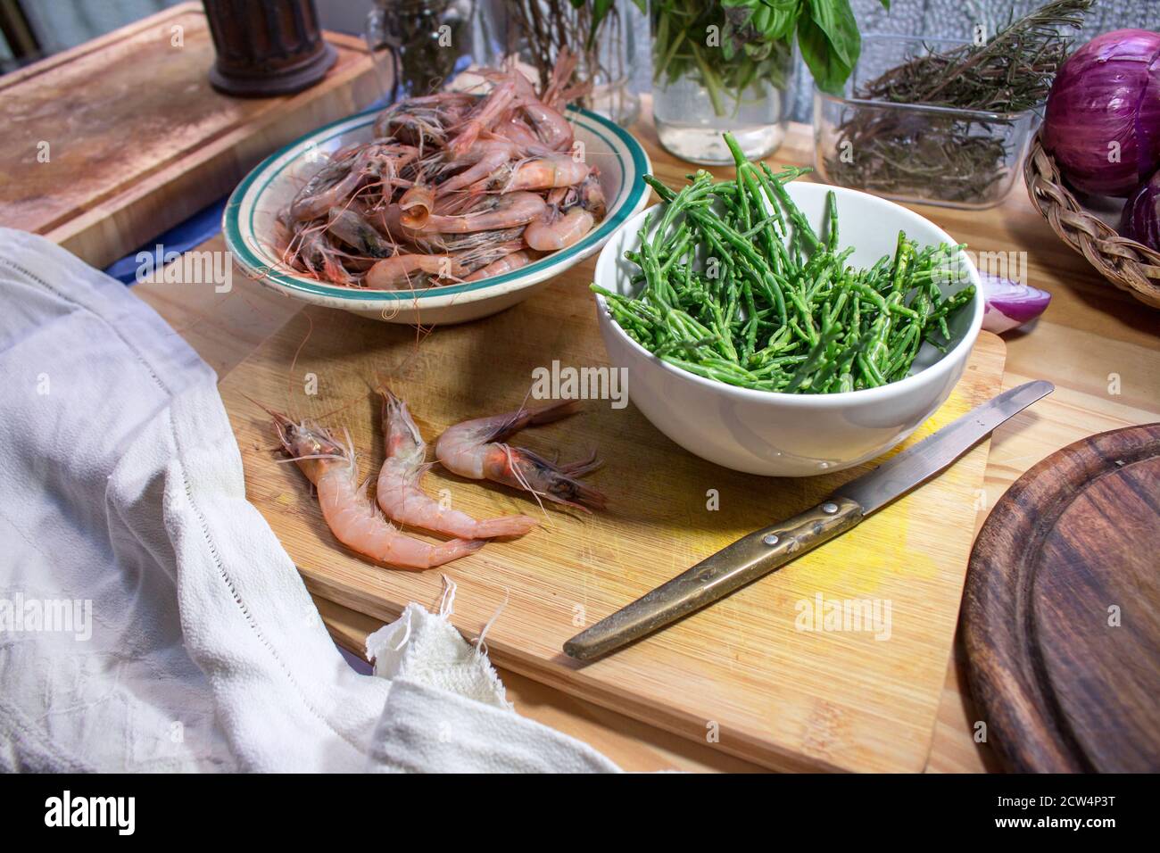 A bowl with salicornia (sea asparagus) and a plate full of Mediterranean shrimp on a wooden surface Stock Photo