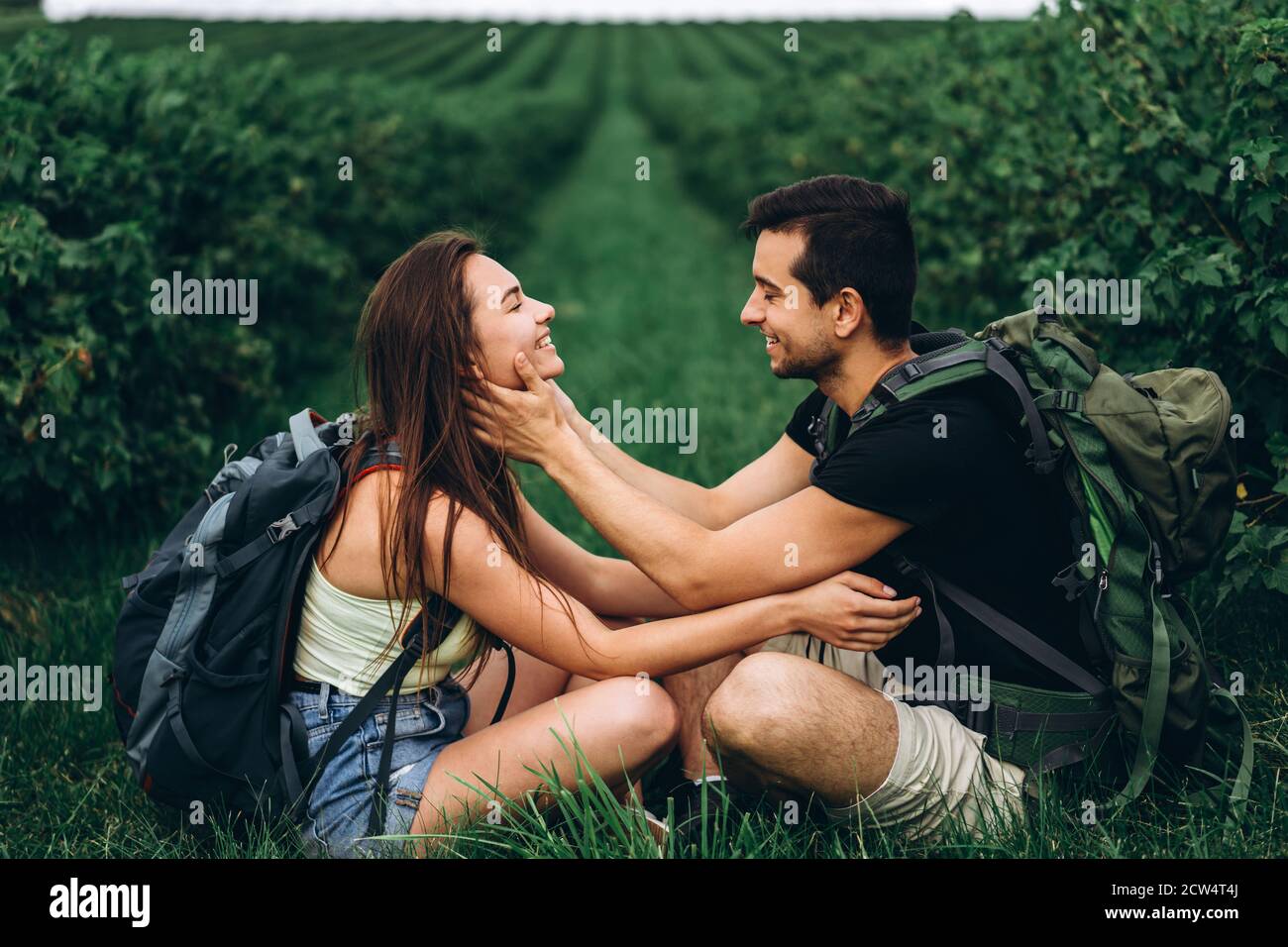 Man and woman with backpacks on their backs sitting hugging on the ...