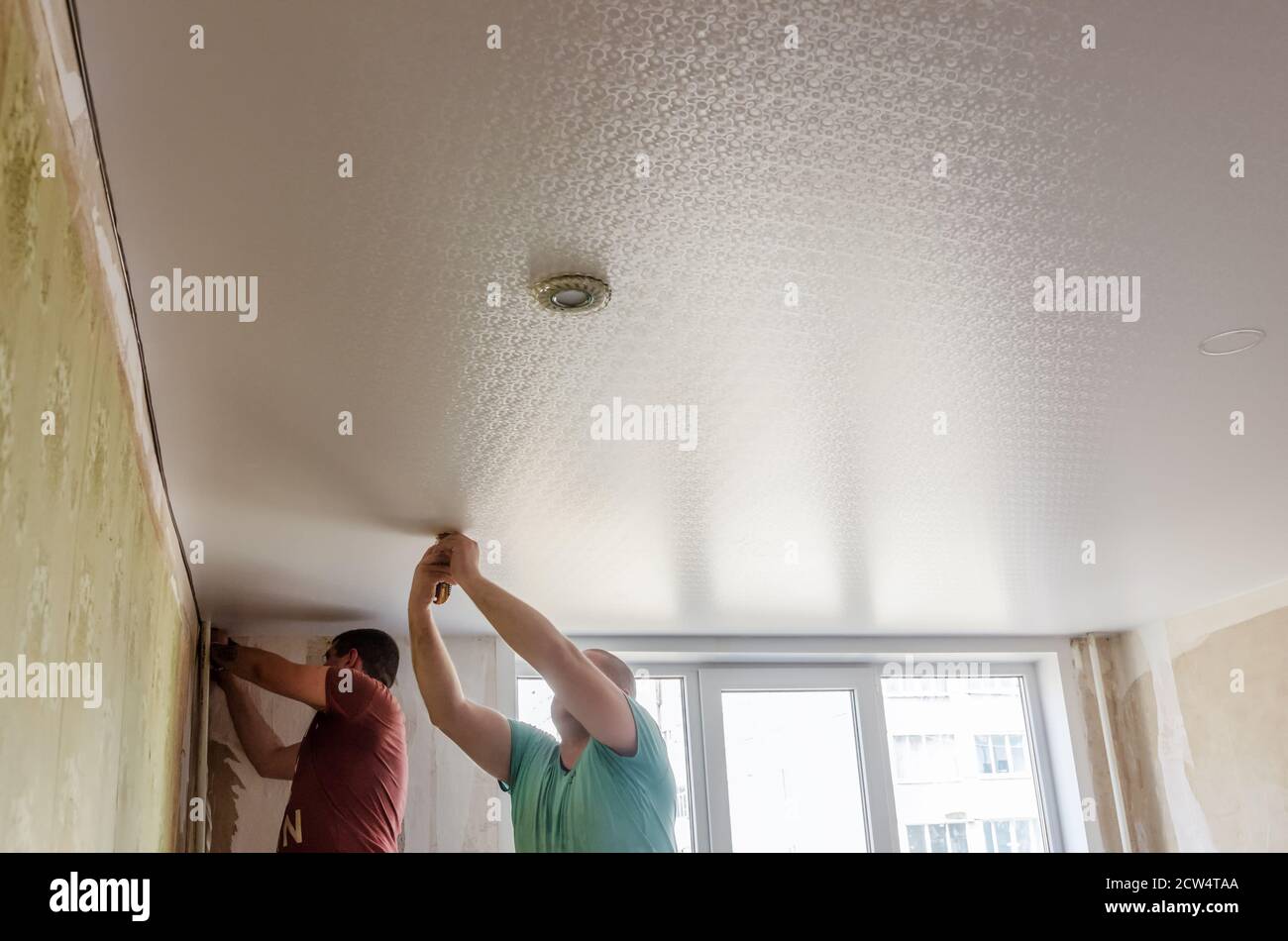 installation of spotlights on a stretch vinyl white ceiling Stock Photo -  Alamy