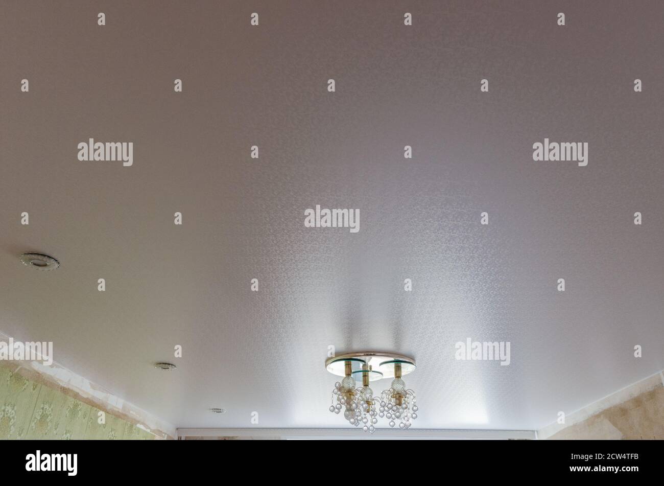 Ceiling in a room with spotlights and a chandelier mounted and turned off Stock Photo