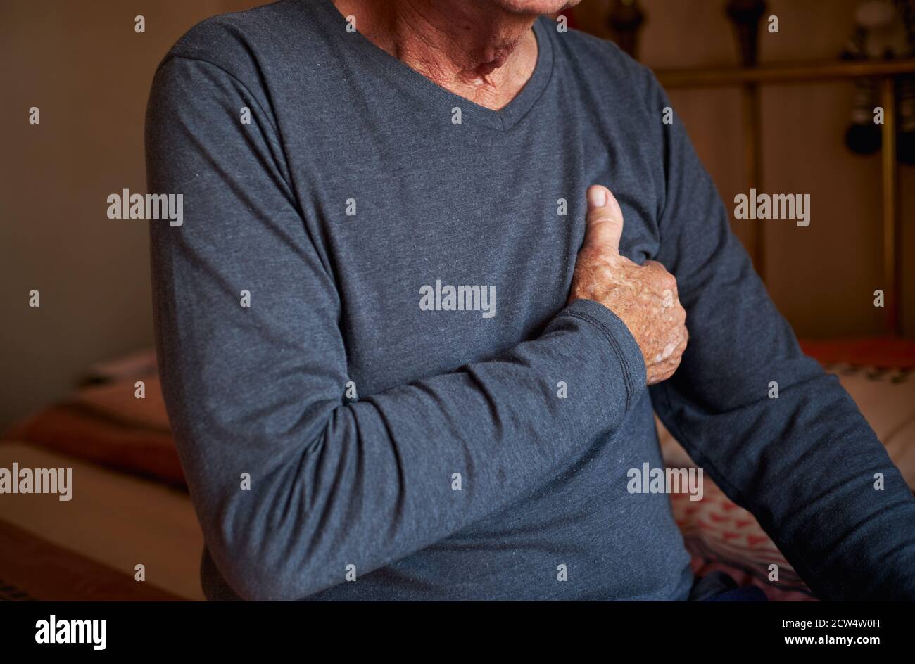 Close Up Of Senior Man With Health Issues At Home Clutching Chest In Pain Stock Photo