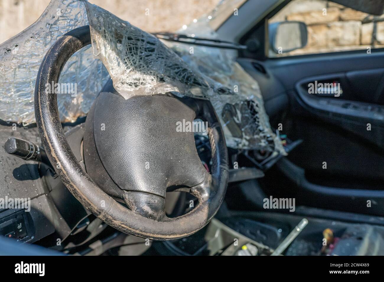 Completely destroyed car. The windshield is broken and lies inside the car Stock Photo