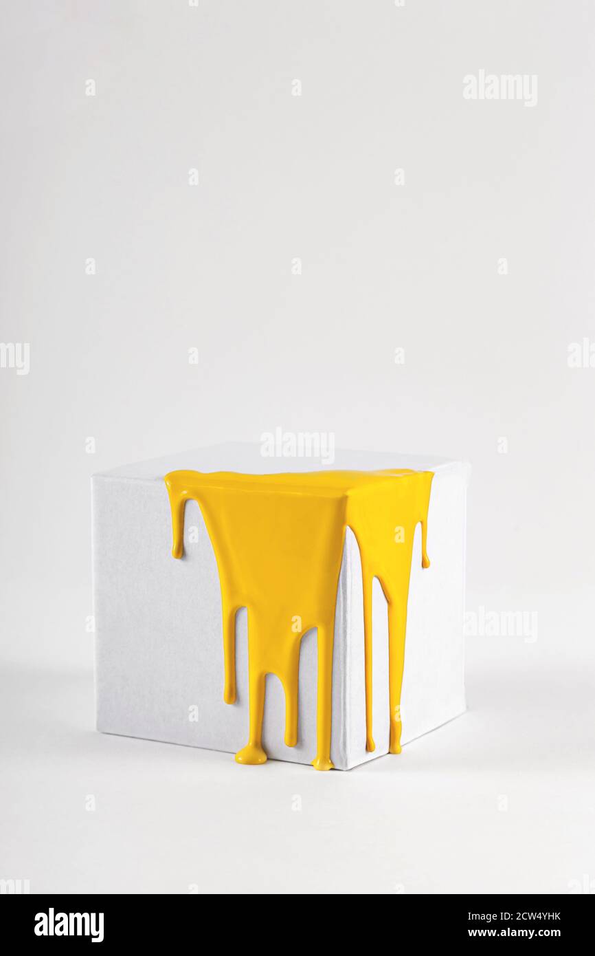 White cube with smudges of bright yellow paint Stock Photo