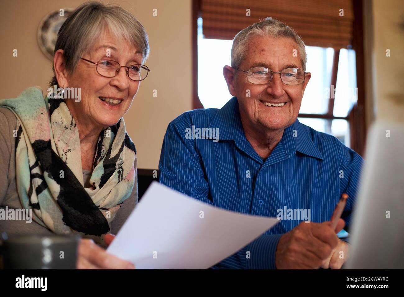 Smiling Senior Couple At Home Checking Personal Finances On Laptop Stock Photo
