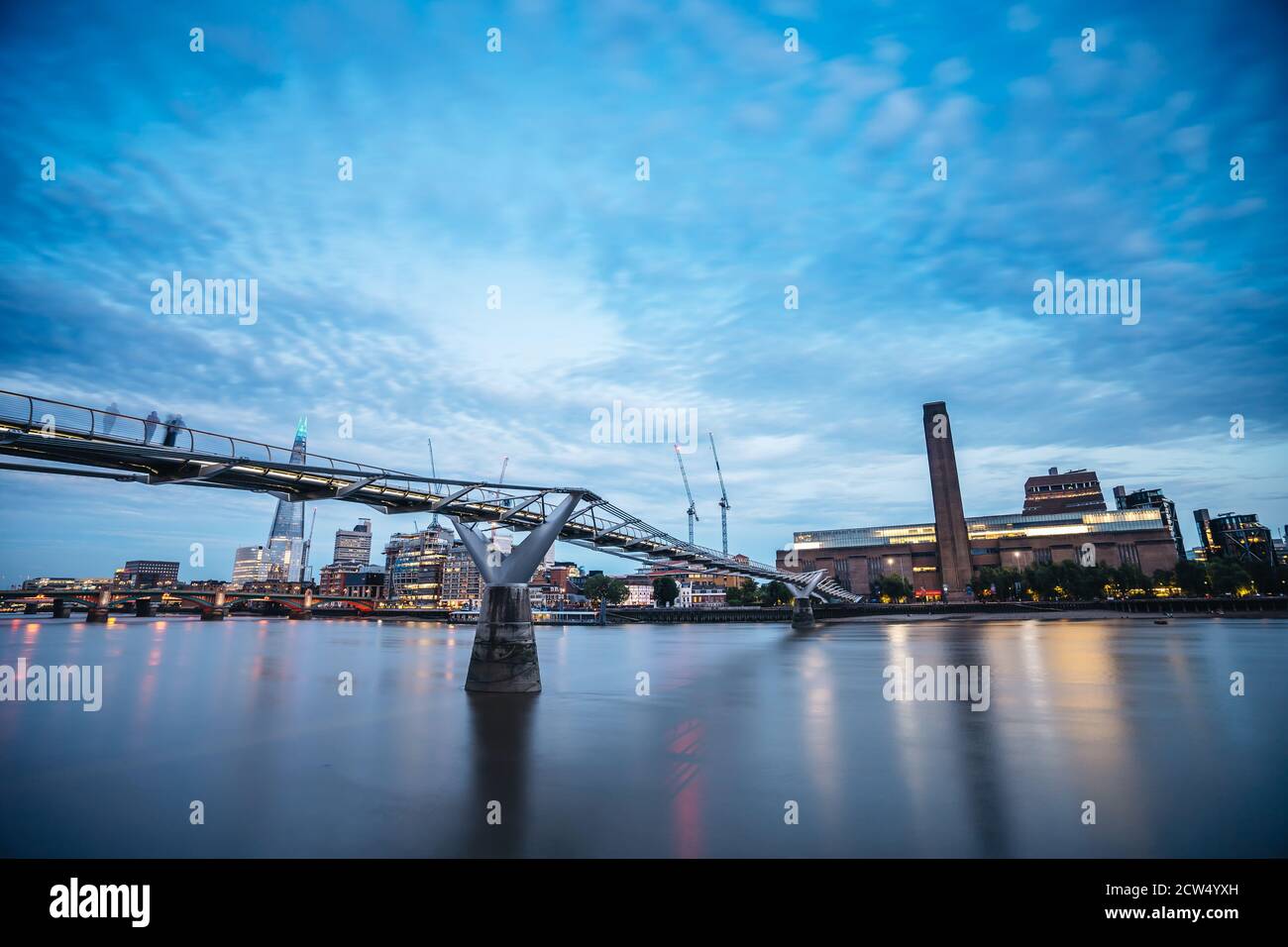 London / UK -  2020.07.18: View of Tate Modern and Thames river behind Millennium Bridge in the eveing with ice blue cloudy sky Stock Photo