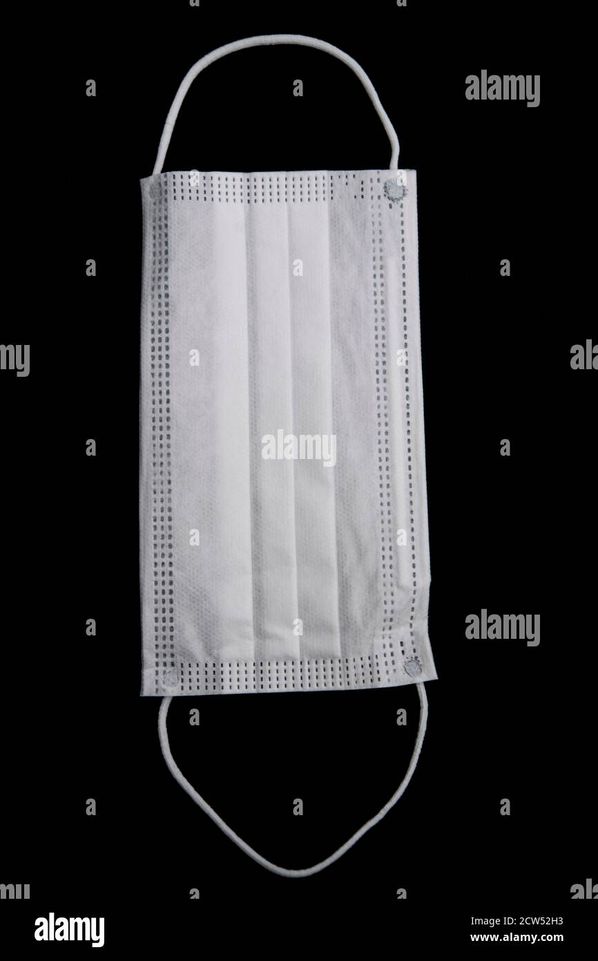 White protective face mask isolated on a black background Stock Photo