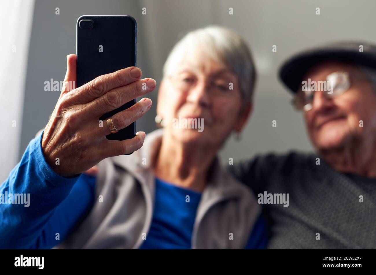 Senior Couple At Home Making Video Call To Family On Mobile Phone Stock Photo