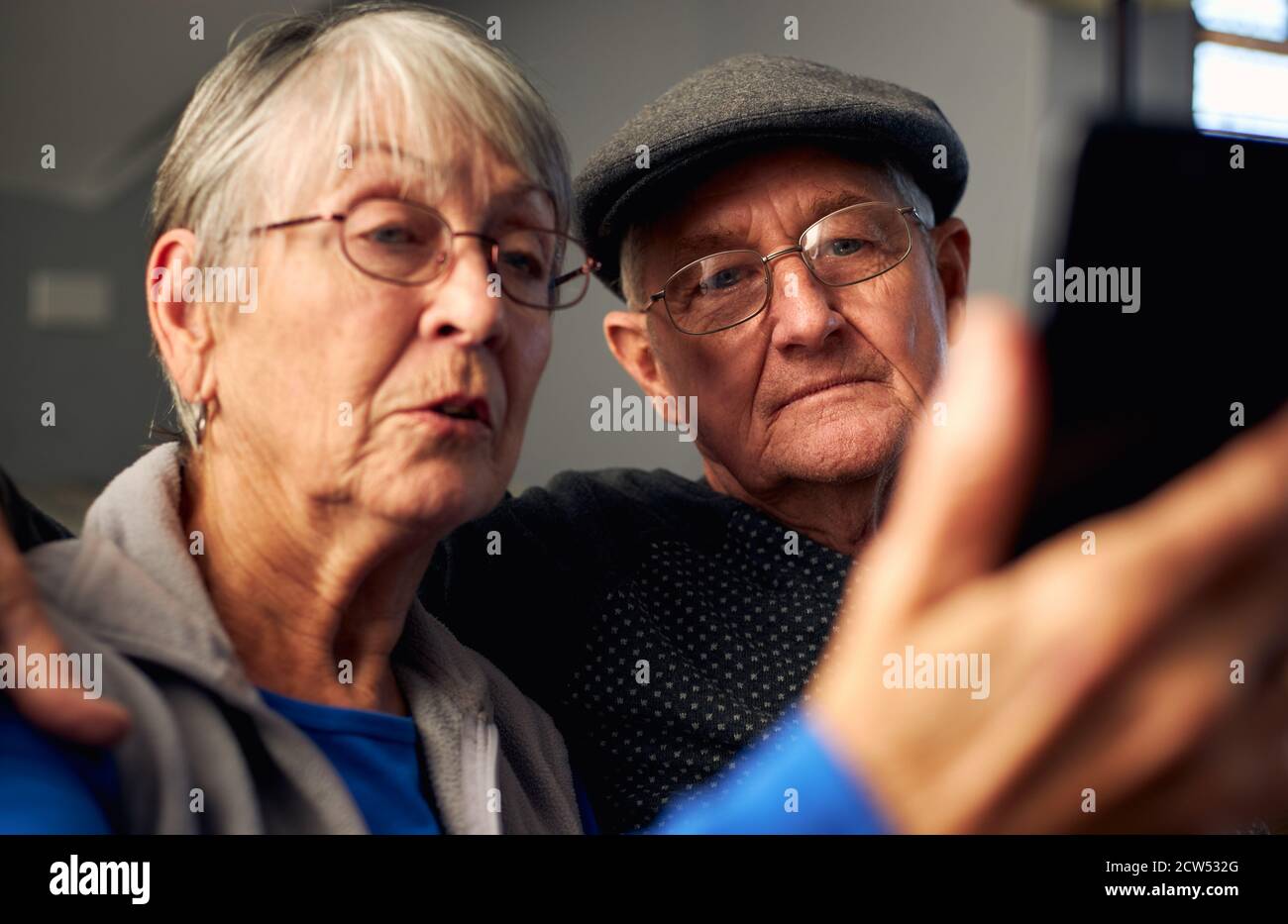 Senior Couple At Home Making Video Call To Family On Mobile Phone Stock Photo