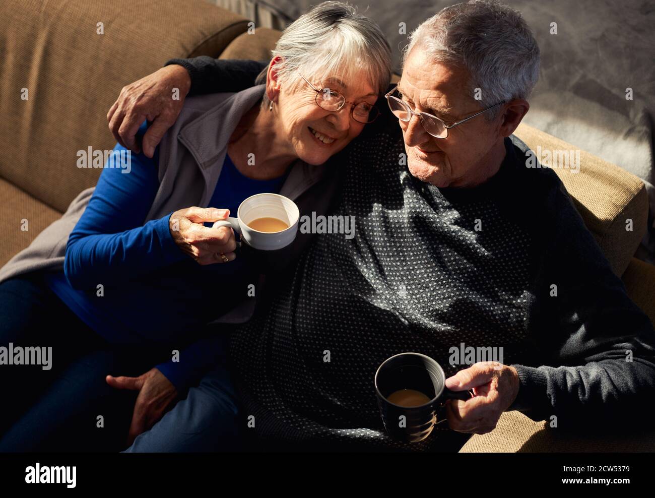 Loving Senior Couple Relaxing And Chatting On Sofa At Home Together ...